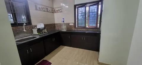 L-shaped kitchen with a sink, dark worktop, dish rack and two grilled windows