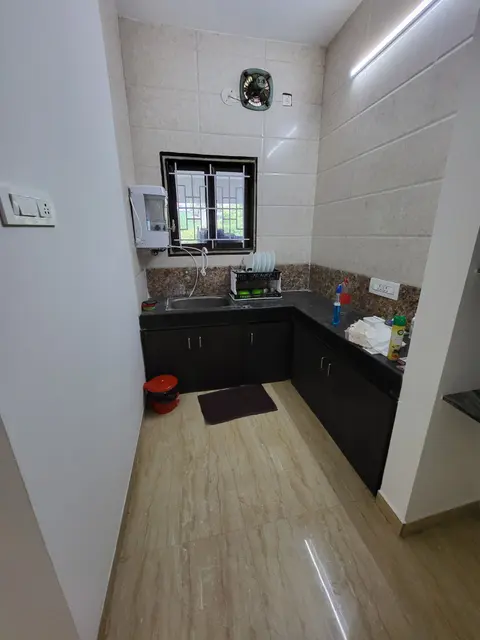 Kitchen with an L-shaped dark counter, wall-mounted water purifier, small oven and grilled window