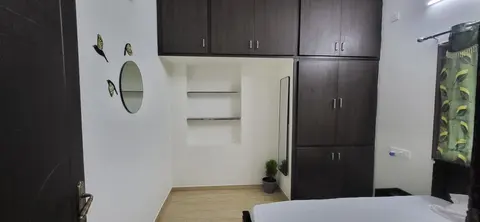 Master bedroom with built-in wardrobe and loft cabinets, open wall shelves and patterned curtains