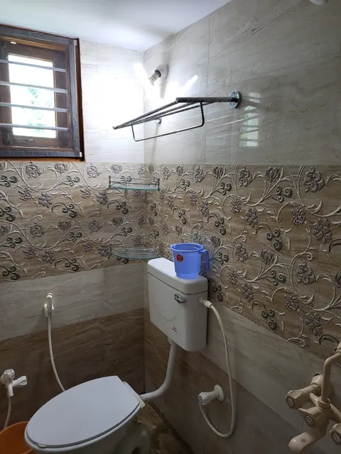 Western WC below a small window with a towel rail and patterned wall tiles